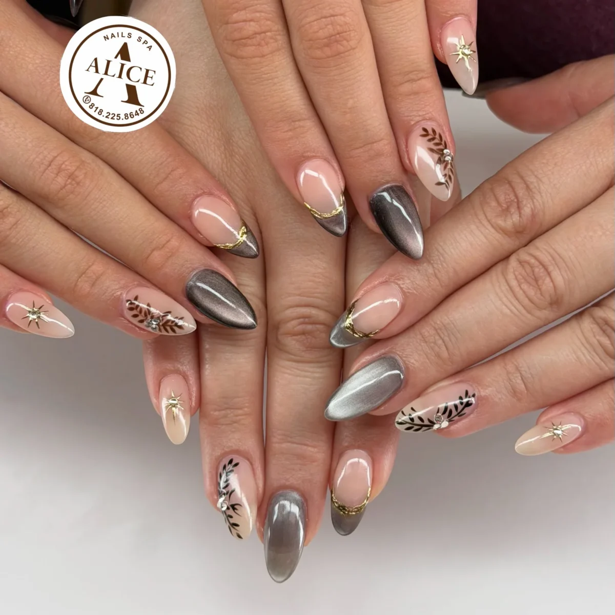 Two sets of almond nails together: grey and taupe cat-eye, nude with cat-eye French tips edged in gold foil, hand-painted brown and black leaves with rhinestones, and gold star studs
