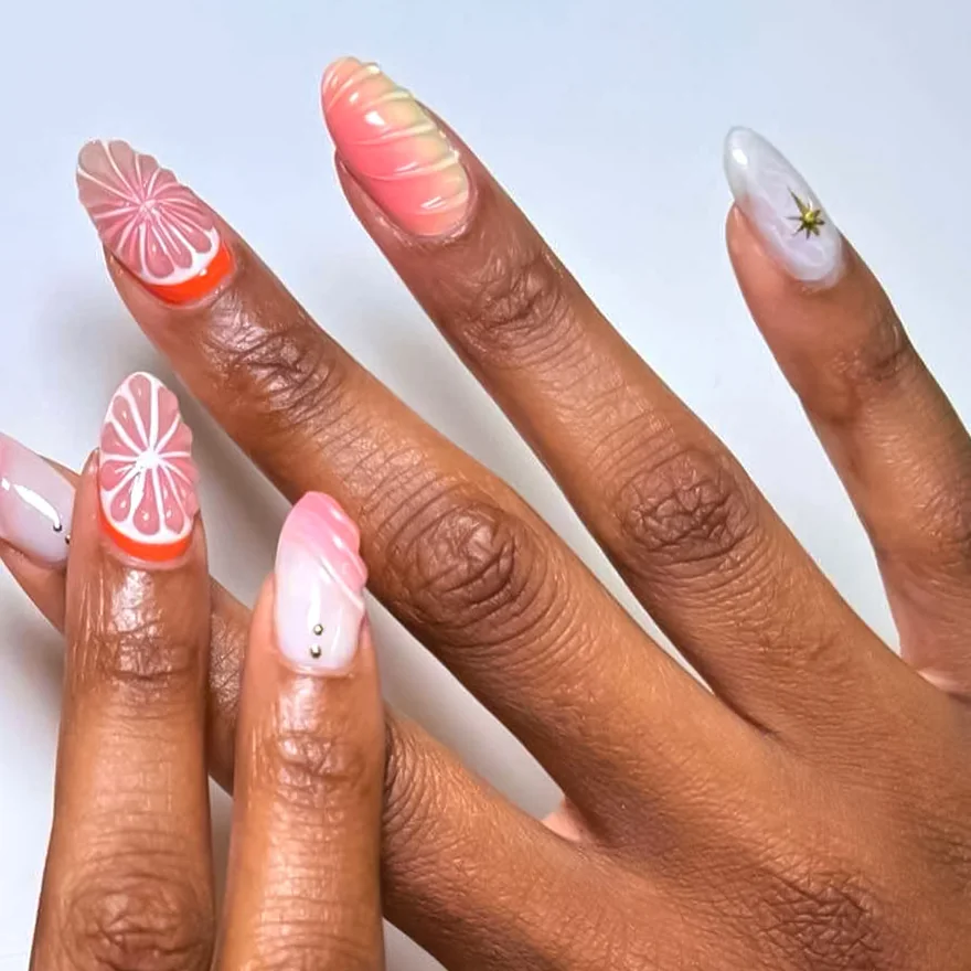Almond nails with hand-painted grapefruit slices, a pink swirl and a small gold star