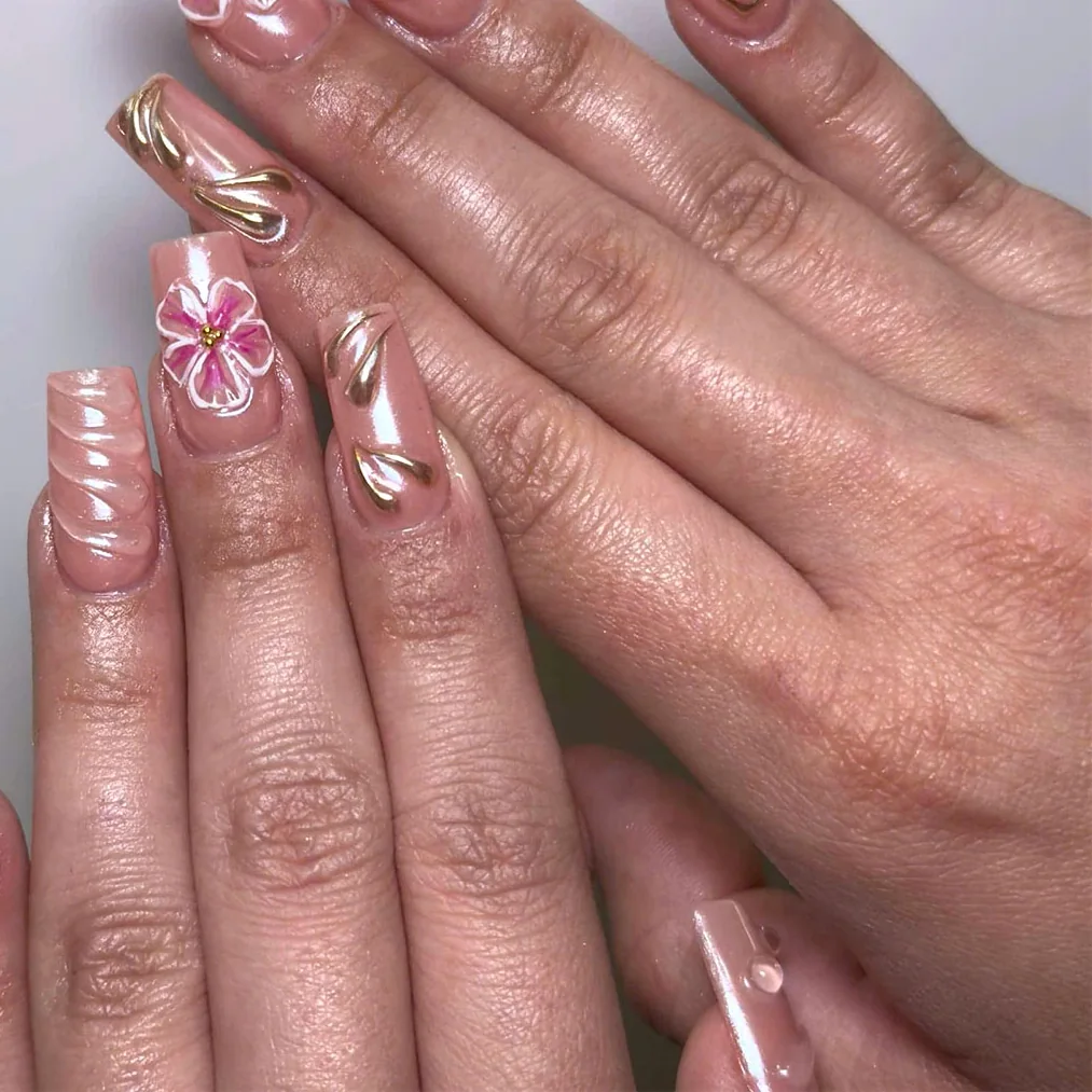 Nude coffin nails with a painted pink hibiscus, gold chrome swirls and gold outlines