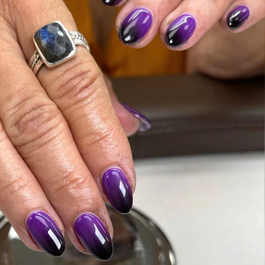 Short almond nails in a deep purple ombré, a hand with a silver ring